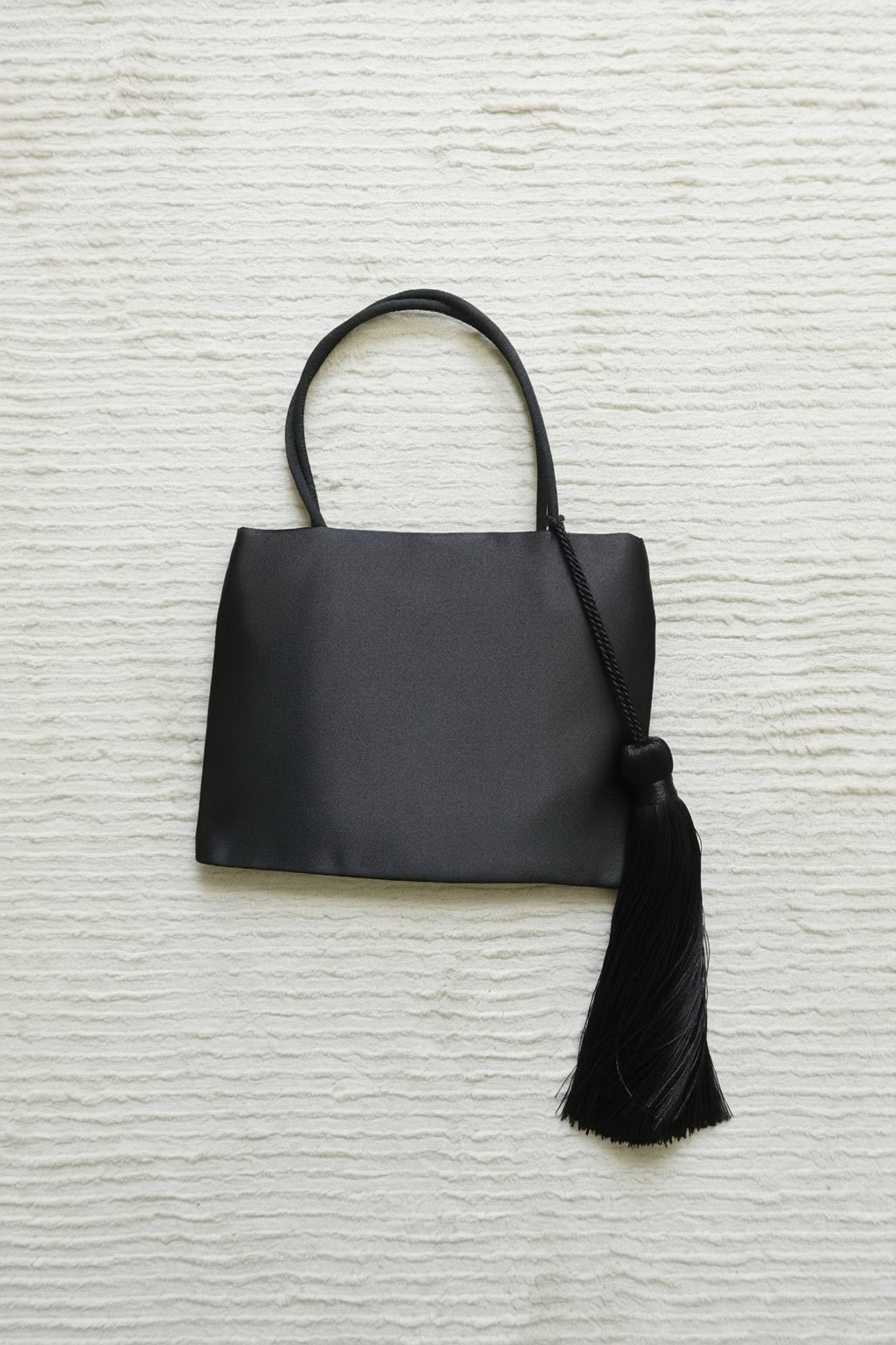 Minimalist Black Nylon Top Handle Bag with Statement Silk Tassel Accent