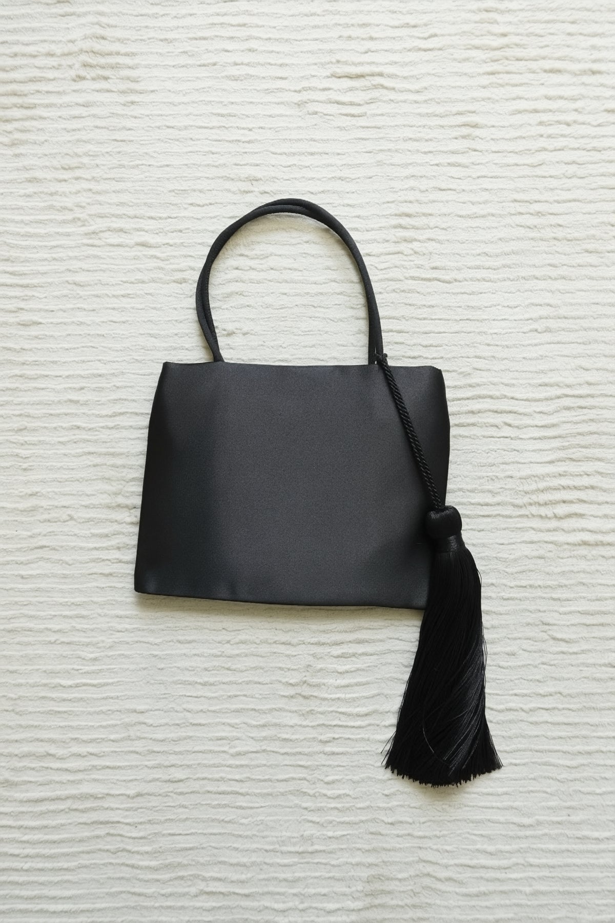 Minimalist Black Nylon Top Handle Bag with Statement Silk Tassel Accent
